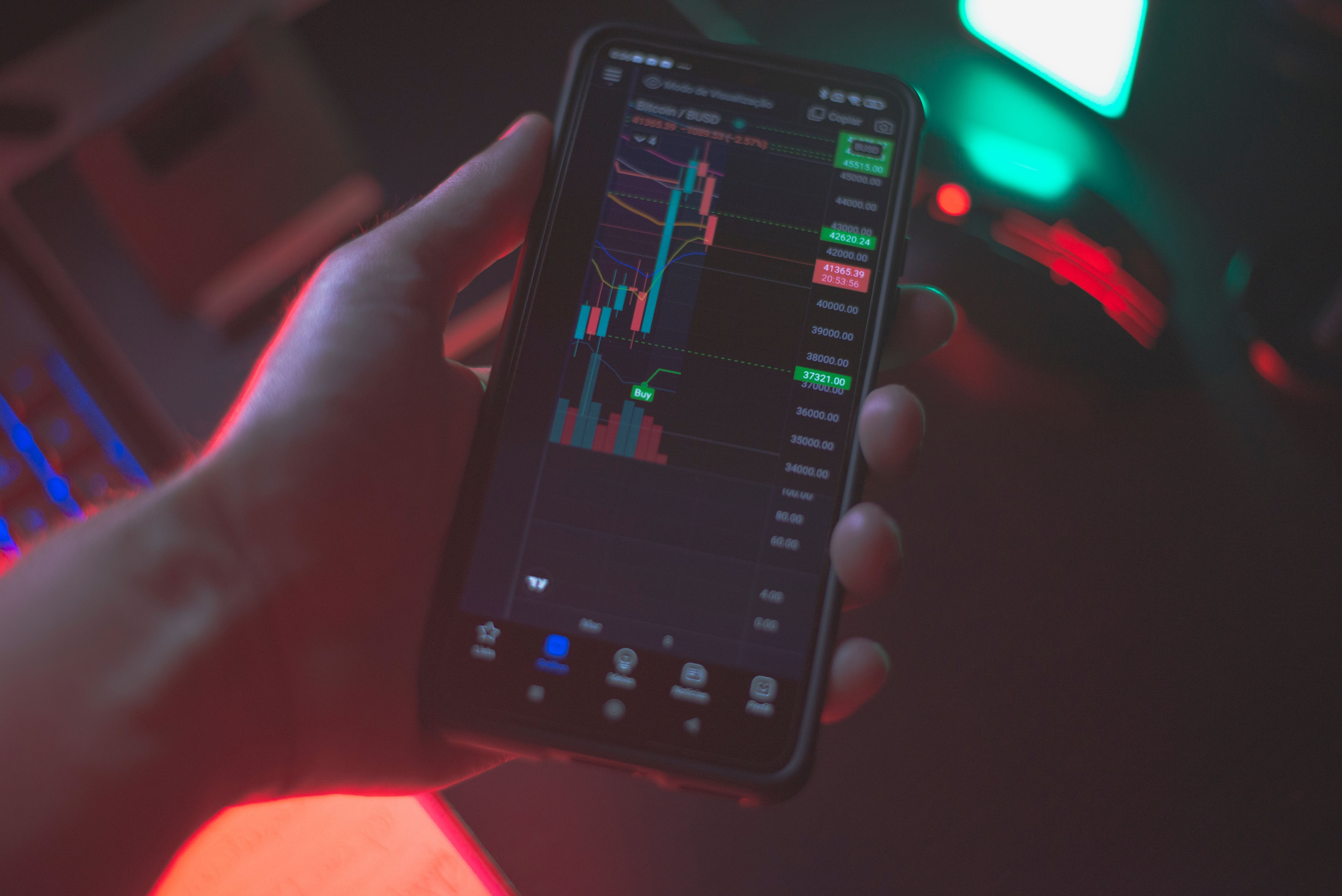 Une main tient un smartphone affichant une application d’échange de cryptomonnaies